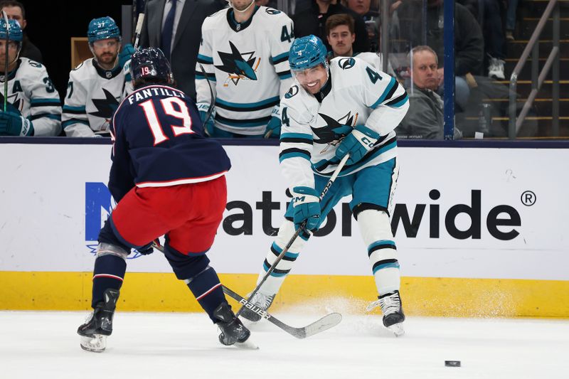 Jan 16, 2025; Columbus, Ohio, USA;  San Jose Sharks defenseman Cody Ceci (4) passes the puck as Columbus Blue Jackets center Adam Fantilli (19) defends during the first period at Nationwide Arena. Mandatory Credit: Joseph Maiorana-Imagn Images