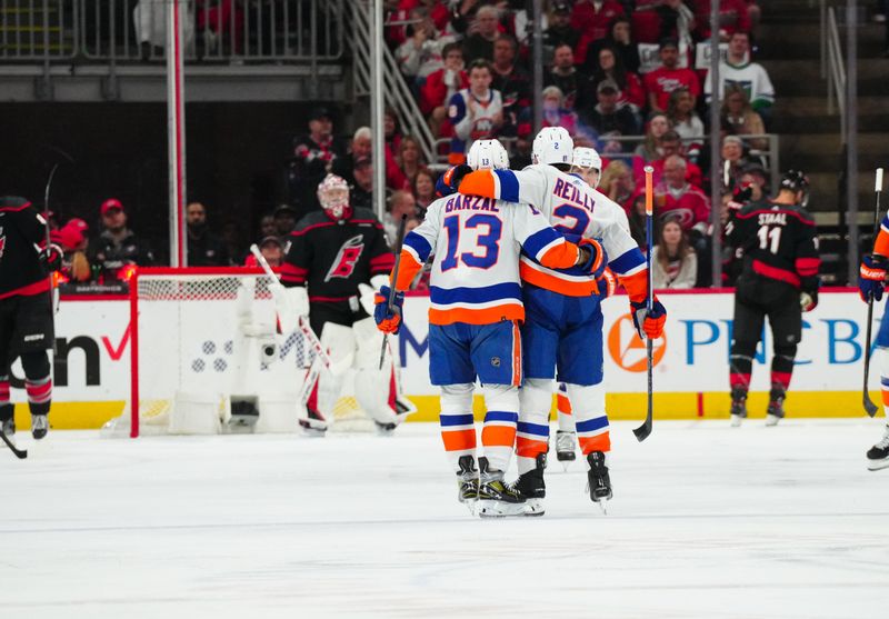 Apr 30, 2024; Raleigh, North Carolina, USA; New York Islanders defenseman Mike Reilly (2) is congratulated by center Mathew Barzal (13) after his goal against the Carolina Hurricanes during the first period in game five of the first round of the 2024 Stanley Cup Playoffs at PNC Arena. Mandatory Credit: James Guillory-USA TODAY Sports