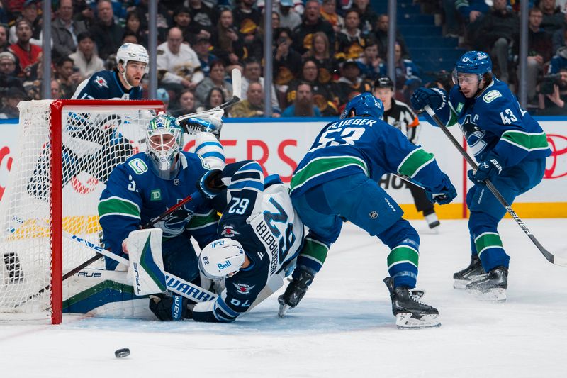 Mar 18, 2025; Vancouver, British Columbia, CAN; Vancouver Canucks defenseman Quinn Hughes (43) watches as goalie Kevin Lankinen (32) makes a save while forward Teddy Blueger (53) battles with Winnipeg Jets forward Nino Niederreiter (62) in the first period at Rogers Arena. Mandatory Credit: Bob Frid-Imagn Images