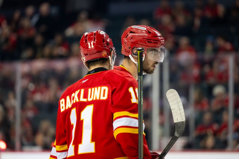 Oct 20, 2025; Calgary, Alberta, CAN; Calgary Flames center Mikael Backlund (11) and Calgary Flames defenseman Kevin Bahl (7) talk before a faceoff against the Winnipeg Jets during the first period at Scotiabank Saddledome. Mandatory Credit: Brett Holmes-Imagn Images