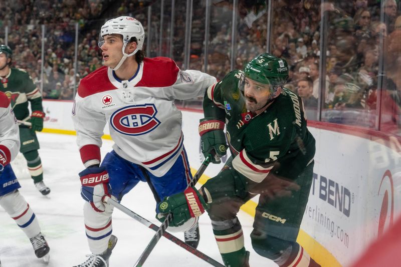 Dec 21, 2023; Saint Paul, Minnesota, USA; Minnesota Wild defenseman Jake Middleton (5) clears the puck with Montreal Canadiens left wing Juraj Slafkovsky (20) in the second period at Xcel Energy Center. Mandatory Credit: Matt Blewett-USA TODAY Sports