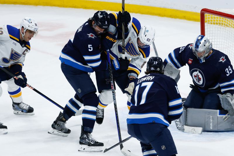 Feb 27, 2024; Winnipeg, Manitoba, CAN; Winnipeg Jets defenseman Brenden Dillon (5) and St. Louis Blues forward Jake Neighbours (63) fight for the puck during the third period at Canada Life Centre. Mandatory Credit: Terrence Lee-USA TODAY Sports