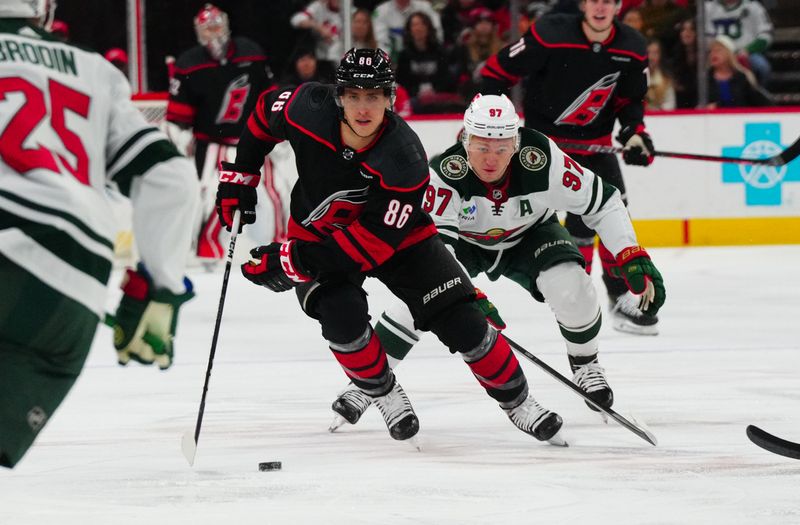 Jan 21, 2024; Raleigh, North Carolina, USA; Carolina Hurricanes left wing Teuvo Teravainen (86) skates with the puck past Minnesota Wild left wing Kirill Kaprizov (97) during the first period at PNC Arena. Mandatory Credit: James Guillory-USA TODAY Sports