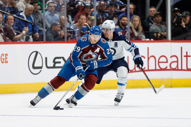 Apr 26, 2024; Denver, Colorado, USA; Colorado Avalanche center Nathan MacKinnon (29) controls the puck ahead of Winnipeg Jets center Mark Scheifele (55) in the first period in game three of the first round of the 2024 Stanley Cup Playoffs at Ball Arena. Mandatory Credit: Isaiah J. Downing-USA TODAY Sports