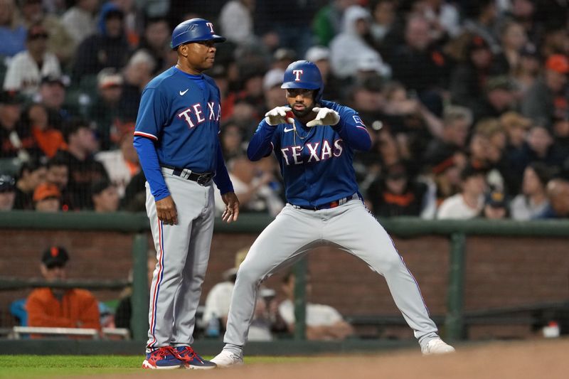 Aug 12, 2023; San Francisco, California, USA; Texas Rangers designated hitter Ezequiel Duran (right) gestures after hitting a triple against the San Francisco Giants as third base coach Tony Beasley (left) stands next to him during the eighth inning at Oracle Park. Mandatory Credit: Darren Yamashita-USA TODAY Sports