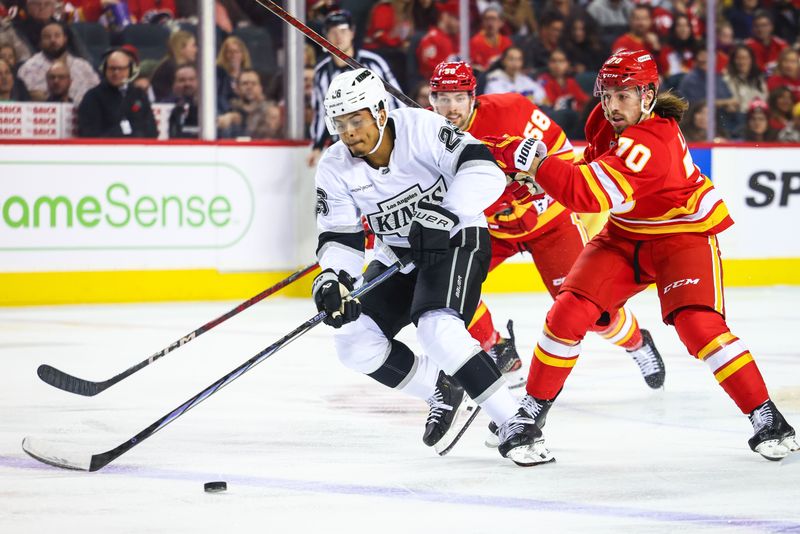 Nov 11, 2024; Calgary, Alberta, CAN; Los Angeles Kings center Akil Thomas (26) and Calgary Flames left wing Ryan Lomberg (70) battles for the puck during the first period at Scotiabank Saddledome. Mandatory Credit: Sergei Belski-Imagn Images