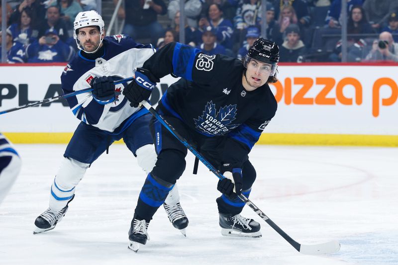 Oct 28, 2024; Winnipeg, Manitoba, CAN; Toronto Maple Leafs forward Matthew Knies (23) jostles for position with Winnipeg Jets defenseman Dylan DeMelo (2) during the first period at Canada Life Centre. Mandatory Credit: Terrence Lee-Imagn Images