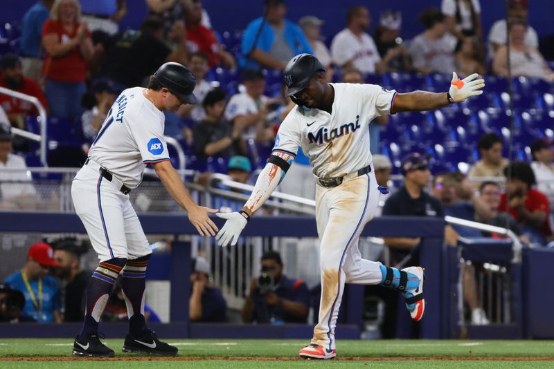 Jul 4, 2024; Miami, Florida, USA; Miami Marlins right fielder Jesus Sanchez (12) celebrates with third base coach Griffin Benedict (81) after hitting a two-run home run against the Boston Red Sox during the eleventh inning at loanDepot Park. Mandatory Credit: Sam Navarro-USA TODAY Sports