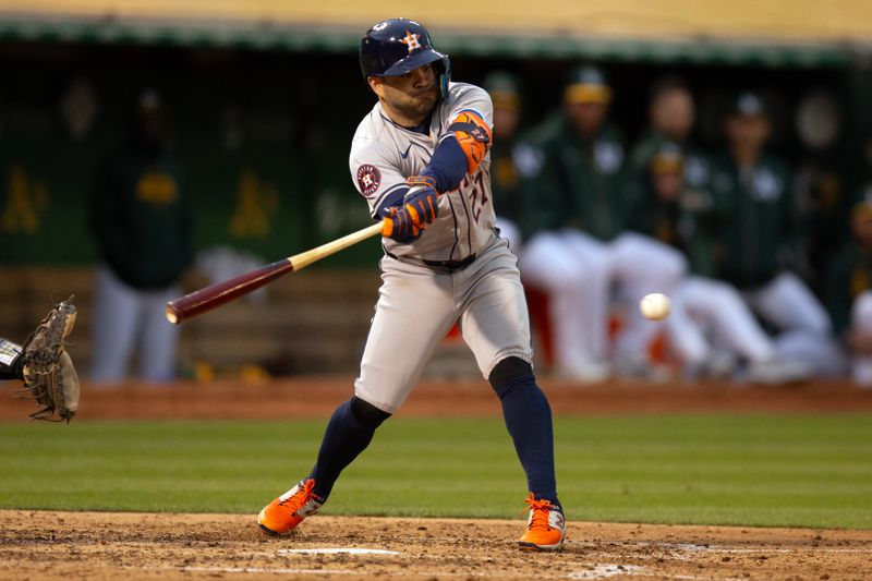 May 24, 2024; Oakland, California, USA; Houston Astros second baseman Jose Altuve (27) connects for a single, his second of the inning against the Oakland Athletics, during the fourth inning at Oakland-Alameda County Coliseum. Mandatory Credit: D. Ross Cameron-USA TODAY Sports