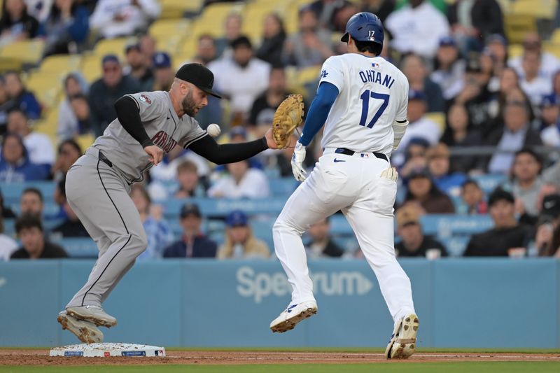 May 20, 2024; Los Angeles, California, USA;  Los Angeles Dodgers designated hitter Shohei Ohtani (17) singles on a bunt as the throw gets past Arizona Diamondbacks first baseman Christian Walker (53) in the first inning at Dodger Stadium. Mandatory Credit: Jayne Kamin-Oncea-USA TODAY Sports