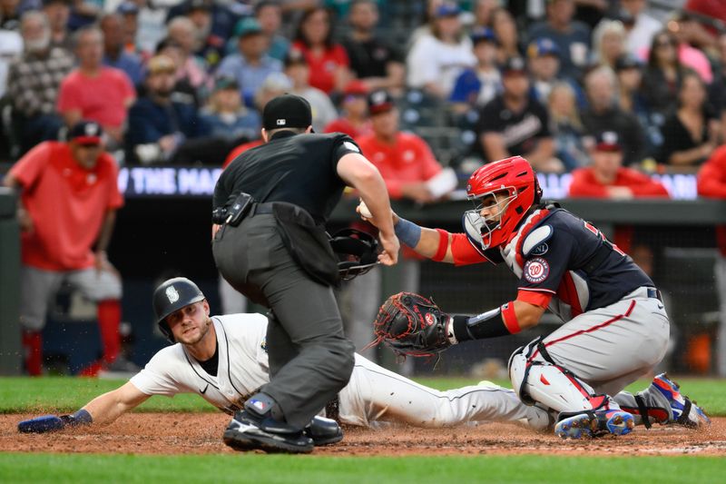 Jun 27, 2023; Seattle, Washington, USA; Seattle Mariners left fielder Jarred Kelenic (10) slides past Washington Nationals catcher Keibert Ruiz (20) to score a run during the seventh inning at T-Mobile Park. Mandatory Credit: Steven Bisig-USA TODAY Sports