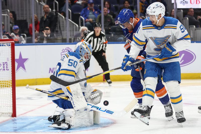 Nov 22, 2025; Elmont, New York, USA; St. Louis Blues goaltender Jordan Binnington (50) defends the net as left wing Anders Lee (27) and St. Louis Blues defenseman Matthew Kessel (51) battle for control of the puck in the second period at UBS Arena. Mandatory Credit: Wendell Cruz-Imagn Images