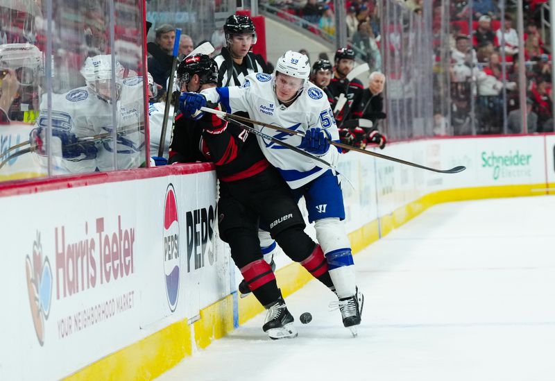 Oct 11, 2024; Raleigh, North Carolina, USA;  Tampa Bay Lightning center Jake Guentzel (59) checks Carolina Hurricanes defenseman Sean Walker (26) during the third period at PNC Arena. Mandatory Credit: James Guillory-Imagn Images