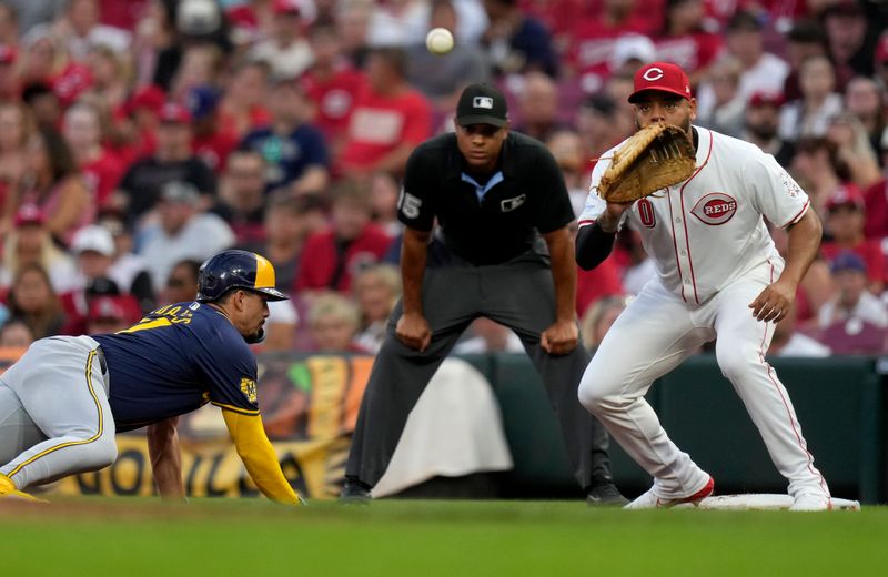 Aug 31, 2024; Cincinnati, Ohio, USA; Milwaukee Brewers shortstop Willy Adames (27) slides back to first base safely as Cincinnati Reds first baseman Dominic Smith (0) waits for the catch in the first inning at Great American Ball Park. Mandatory Credit: Cara Owsley/The Cincinnati Enquirer-USA TODAY Sports