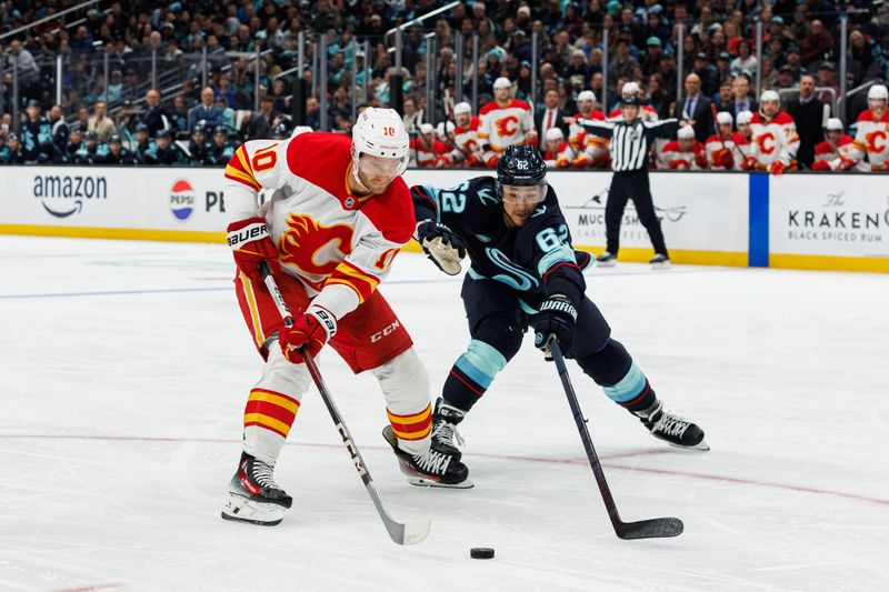 Oct 19, 2024; Seattle, Washington, USA; Calgary Flames center Jonathan Huberdeau (10) skates with the puck as Seattle Kraken defenseman Brandon Montour (62) defends during the second period at Climate Pledge Arena. Mandatory Credit: Caean Couto-Imagn Images