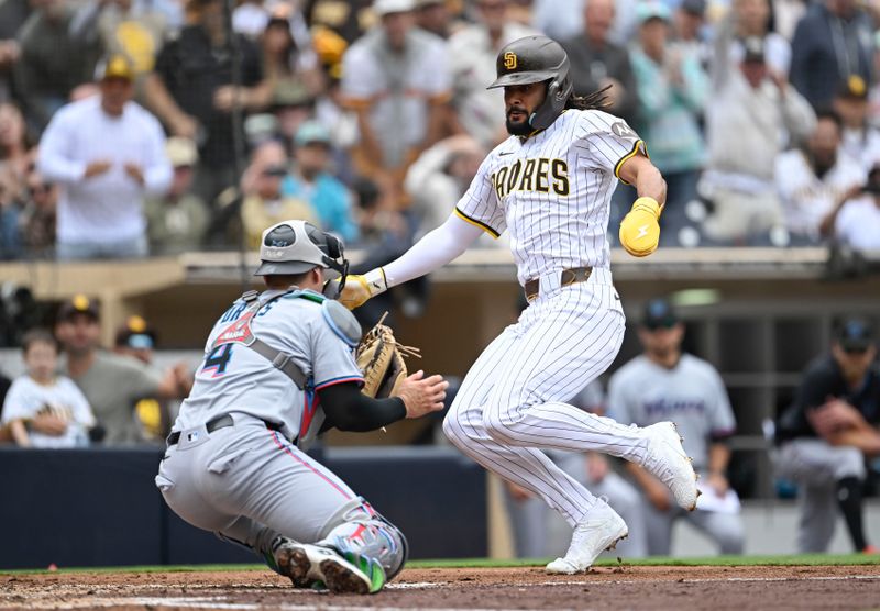 May 28, 2025; San Diego, California, USA; San Diego Padres right fielder Fernando Tatis Jr. (23) is tagged out at the plate by Miami Marlins catcher Nick Fortes (4) during the fourth inning at Petco Park. Mandatory Credit: Denis Poroy-Imagn Images