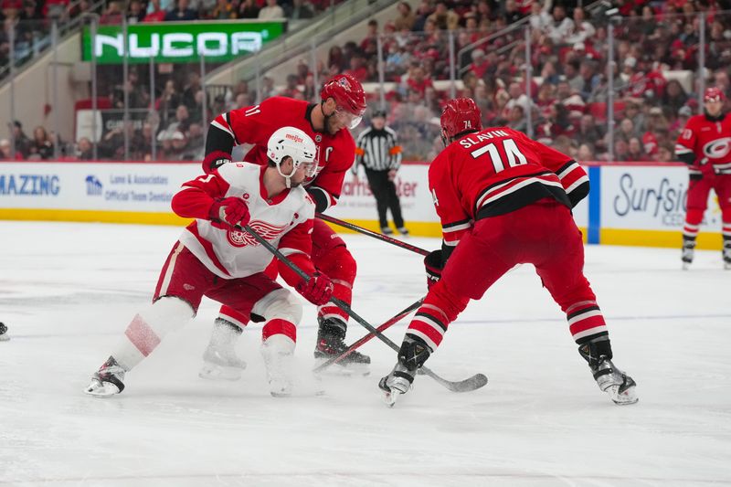 Feb 28, 2026; Raleigh, North Carolina, USA;  Carolina Hurricanes center Jordan Staal (11) and defenseman Jaccob Slavin (74) take the puck away from Detroit Red Wings center Dylan Larkin (71) during the second period at Lenovo Center. Mandatory Credit: James Guillory-Imagn Images