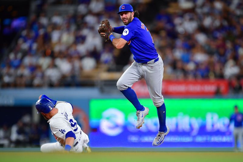 Sep 9, 2024; Los Angeles, California, USA; Los Angeles Dodgers second baseman Gavin Lux (9) is out at second as Chicago Cubs shortstop Dansby Swanson (7) throws to first for the out against shortstop Miguel Rojas (11) during the sixth inning at Dodger Stadium. Mandatory Credit: Gary A. Vasquez-Imagn Images