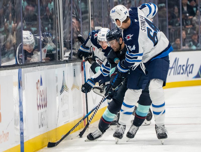 Oct 24, 2024; Seattle, Washington, USA;  Seattle Kraken forward Shane Wright (51) battles Winnipeg Jets forward Morgan Barron (36), left, and defenseman Logan Stanley (64), right, for the puck during the first period at Climate Pledge Arena. Mandatory Credit: Stephen Brashear-Imagn Images