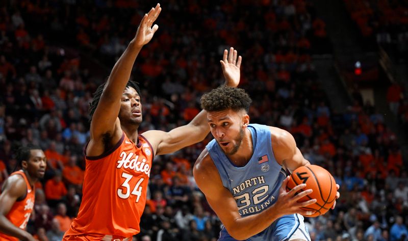 Dec 4, 2022; Blacksburg, Virginia, USA; North Carolina Tar Heels forward Pete Nance (32) drives against Virginia Tech Hokies forward Mylyjael Poteat (34) in the first half at Cassell Coliseum. Mandatory Credit: Lee Luther Jr.-USA TODAY Sports