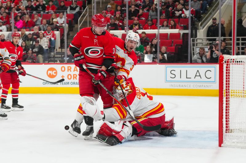 Nov 30, 2025; Raleigh, North Carolina, USA;  Calgary Flames goaltender Devin Cooley (1) and defenseman Yan Kuznetsov (37) stop the shot agin st Carolina Hurricanes right wing Andrei Svechnikov (37) during the first period at Lenovo Center. Mandatory Credit: James Guillory-Imagn Images