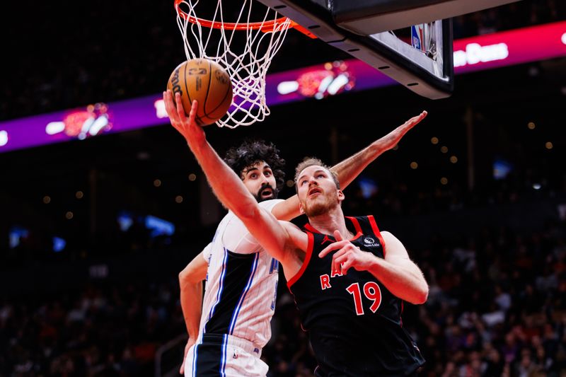 TORONTO, CANADA - JANUARY 3: Jakob Poeltl #19 of the Toronto Raptors goes to the hoop against Goga Bitadze #35 of the Orlando Magic during second half of their NBA game at Scotiabank Arena on January 3, 2025 in Toronto, Canada. NOTE TO USER: User expressly acknowledges and agrees that, by downloading and or using this photograph, User is consenting to the terms and conditions of the Getty Images License Agreement. (Photo by Cole Burston/Getty Images)