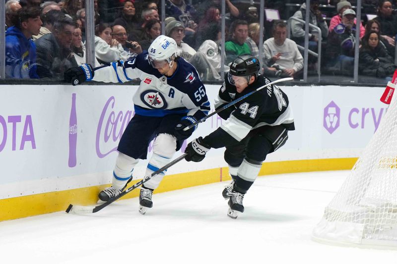 Nov 27, 2024; Los Angeles, California, USA; Winnipeg Jets center Mark Scheifele (55) and LA Kings defenseman Mikey Anderson (44) battle for the puck in the first period at Crypto.com Arena. Mandatory Credit: Kirby Lee-Imagn Images