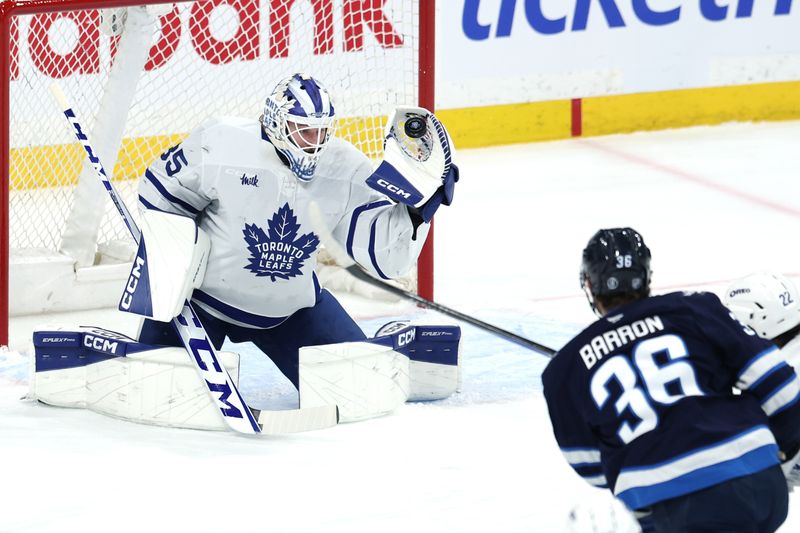 Jan 17, 2026; Winnipeg, Manitoba, CAN; Toronto Maple Leafs goaltender Dennis Hildeby (35) makes a glove save from a shot by Winnipeg Jets center Morgan Barron (36) in the first period at Canada Life Centre. Mandatory Credit: James Carey Lauder-Imagn Images