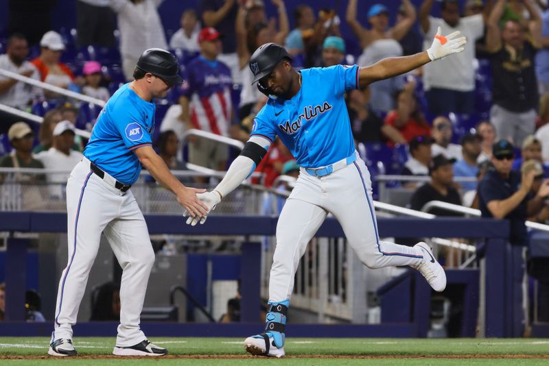 Aug 11, 2024; Miami, Florida, USA; Miami Marlins right fielder Jesus Sanchez (12) celebrates with third base coach Griffin Benedict (81) after hitting a two-run home run against the San Diego Padres during the seventh inning at loanDepot Park. Mandatory Credit: Sam Navarro-USA TODAY Sports