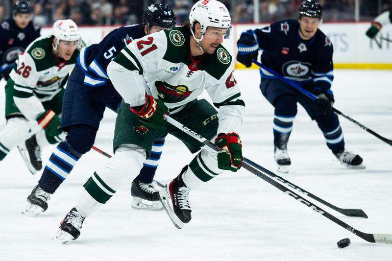 Feb 20, 2024; Winnipeg, Manitoba, CAN; Minnesota Wild forward Brandon Duhaime (21) skates away from Winnipeg Jets forward Mark Scheifele (55) during first period at Canada Life Centre. Mandatory Credit: Terrence Lee-USA TODAY Sports