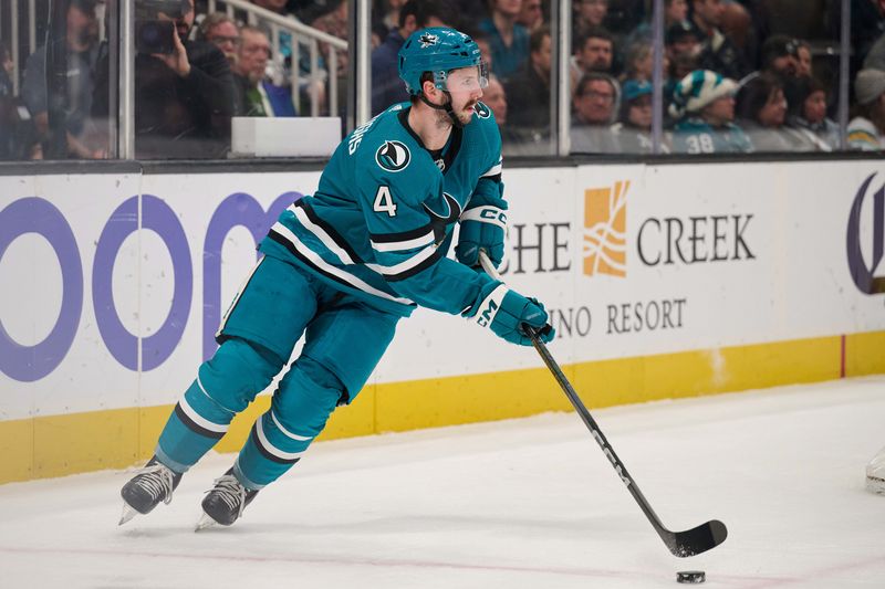 Dec 12, 2023; San Jose, California, USA; San Jose Sharks defenseman Kyle Burroughs (4) skates with the puck against the Winnipeg Jets during the first period at SAP Center at San Jose. Mandatory Credit: Robert Edwards-USA TODAY Sports