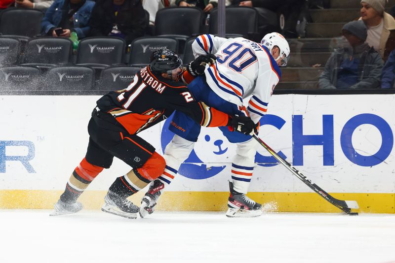 Feb 9, 2024; Anaheim, California, USA; Anaheim Ducks center Isac Lundestrom (21) and Edmonton Oilers right wing Corey Perry (90) fight for the puck during the second period of a game at Honda Center. Mandatory Credit: Jessica Alcheh-USA TODAY Sports