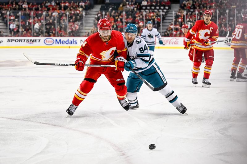 Feb 15, 2024; Calgary, Alberta, CAN; Calgary Flames defenseman Rasmus Andersson (4) and San Jose Sharks left wing Alexander Barabanov (94) compete for the puck during the first period at Scotiabank Saddledome. Mandatory Credit: Brett Holmes-USA TODAY Sports