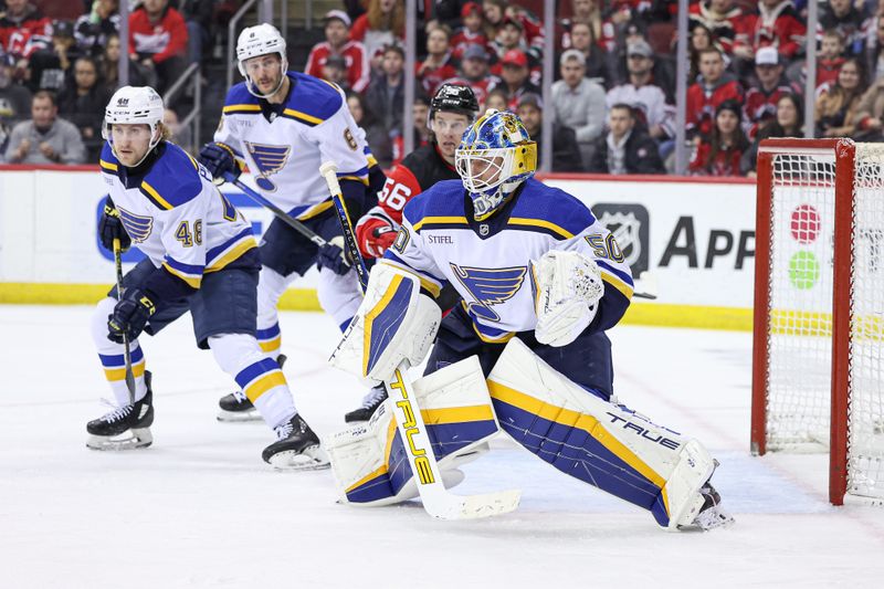 Mar 7, 2024; Newark, New Jersey, USA; St. Louis Blues goaltender Jordan Binnington (50) makes a save in front ofNew Jersey Devils left wing Erik Haula (56) and defenseman Scott Perunovich (48) during the first period at Prudential Center. Mandatory Credit: Vincent Carchietta-USA TODAY Sports