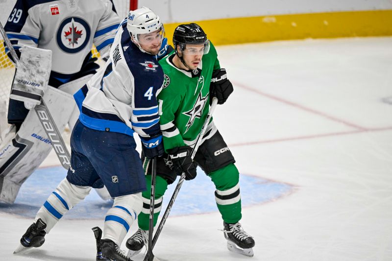 Apr 11, 2024; Dallas, Texas, USA; Winnipeg Jets defenseman Neal Pionk (4) and Dallas Stars center Logan Stankoven (11) battle for position in front of the Winnipeg Jets net during the first period at the American Airlines Center. Mandatory Credit: Jerome Miron-USA TODAY Sports