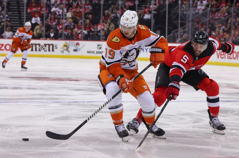 Oct 27, 2024; Newark, New Jersey, USA; Anaheim Ducks right wing Troy Terry (19) skates with the puck while being defended by New Jersey Devils defenseman Brenden Dillon (5) during the first period at Prudential Center. Mandatory Credit: Ed Mulholland-Imagn Images