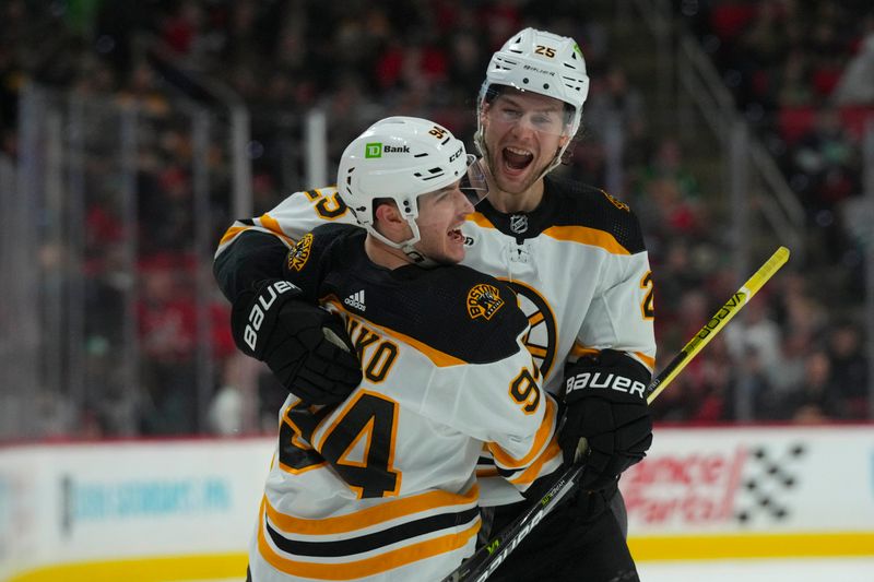 Mar 26, 2023; Raleigh, North Carolina, USA;  Boston Bruins center Jakub Lauko (94) is congratulated by  defenseman Brandon Carlo (25) after his goal against the Carolina Hurricanes during the second period at PNC Arena. Mandatory Credit: James Guillory-USA TODAY Sports