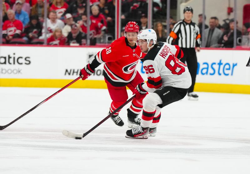 Oct 15, 2024; Raleigh, North Carolina, USA;  New Jersey Devils center Jack Hughes (86) skates with the puck in front of Carolina Hurricanes center Sebastian Aho (20) during the first period at PNC Arena. Mandatory Credit: James Guillory-Imagn Images