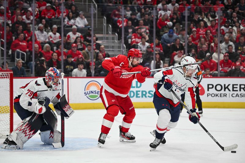 Feb 27, 2024; Detroit, Michigan, USA; Detroit Red Wings center Dylan Larkin (71) battles for the puck against Washington Capitals defenseman Alexander Alexeyev (27) as goaltender Charlie Lindgren (79) attends the net during the second period at Little Caesars Arena. Mandatory Credit: Tim Fuller-USA TODAY Sports