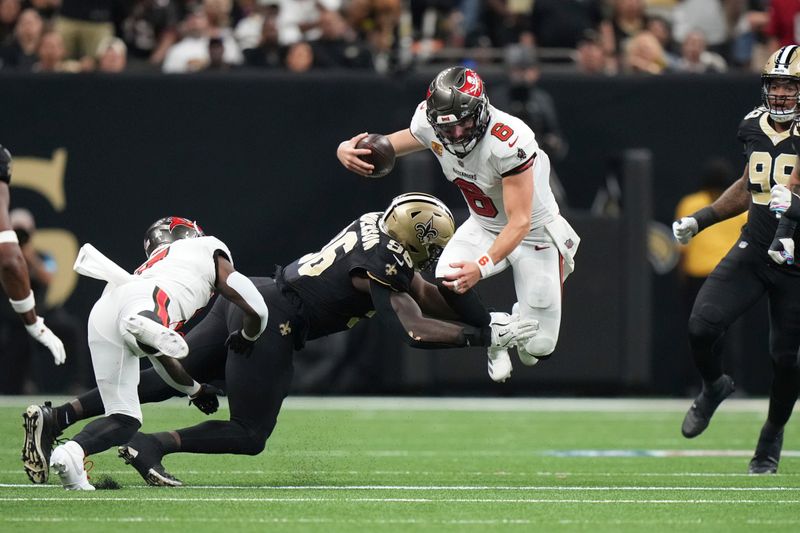 Tampa Bay Buccaneers quarterback Baker Mayfield (6) tries to leap over a tackle attempt by New Orleans Saints defensive end Carl Granderson (96) during an NFL football game, Sunday, October. 13, 2024, in New Orleans, LA. (AP Photo/Peter Joneleit)