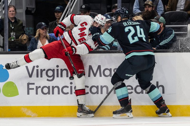 Oct 17, 2022; Seattle, Washington, USA; Seattle Kraken defenseman Jamie Oleksiak (24) collides with Carolina Hurricanes forward Jordan Martinook (A) (48) during the third period at Climate Pledge Arena. Mandatory Credit: Stephen Brashear-USA TODAY Sports