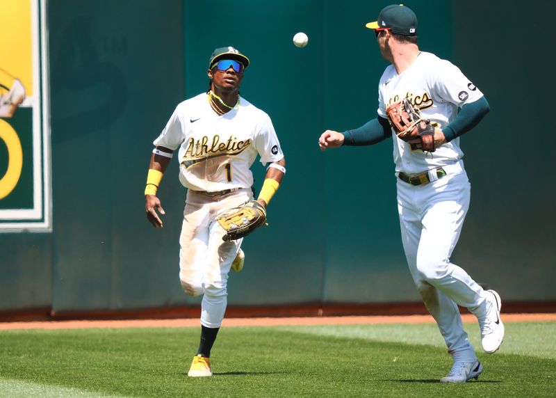 May 31, 2023; Oakland, California, USA; Oakland Athletics center fielder Esteury Ruiz (1) tosses the ball to left fielder Brett Rooker (25) after making an out against the Atlanta Braves during the ninth inning at Oakland-Alameda County Coliseum. Mandatory Credit: Kelley L Cox-USA TODAY Sports