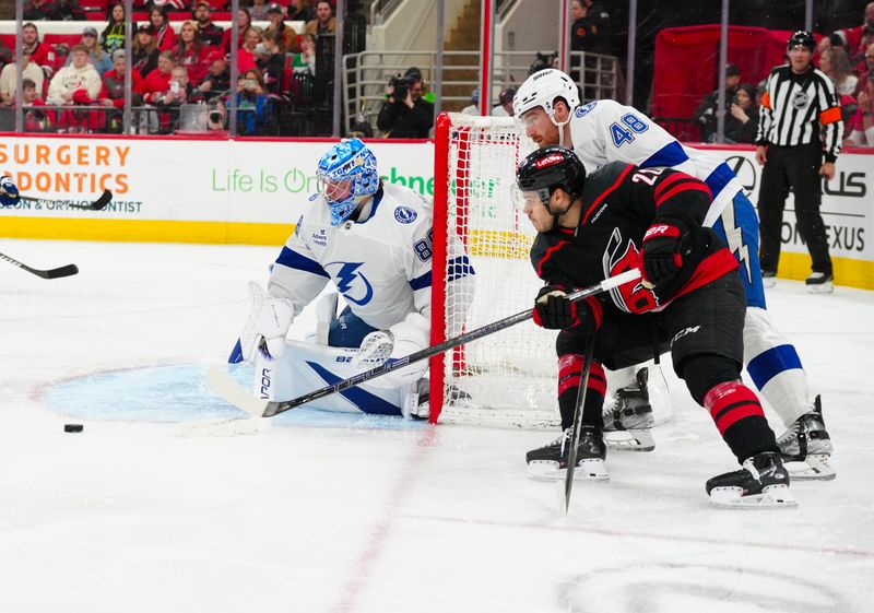 Mar 11, 2025; Raleigh, North Carolina, USA;  Carolina Hurricanes center Logan Stankoven (22) Tampa Bay Lightning defenseman Nick Perbix (48) and goaltender Andrei Vasilevskiy (88) watch the puck during the third period at Lenovo Center. Mandatory Credit: James Guillory-Imagn Images