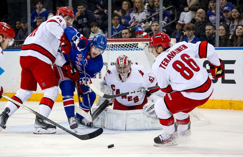 Jan 2, 2024; New York, New York, USA; Carolina Hurricanes goalie Pyotr Kochetkov (52) and New York Rangers forward Alexis Lafreniere (13) eye a loose puck in front of Carolina Hurricanes left wing Teuvo Teravainen (86) during the first period at Madison Square Garden. Mandatory Credit: Danny Wild-USA TODAY Sports