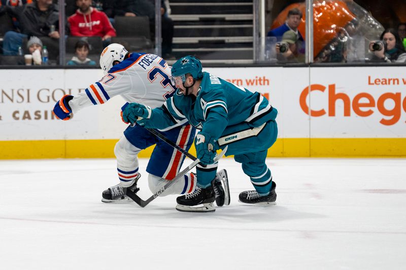 Dec 28, 2023; San Jose, California, USA; Edmonton Oilers left wing Warren Foegele (37) is checked to the ice by San Jose Sharks defenseman Kyle Burroughs (4) during the first period at SAP Center at San Jose. Mandatory Credit: Neville E. Guard-USA TODAY Sports