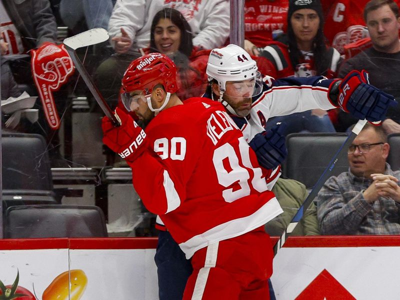 Mar 19, 2024; Detroit, Michigan, USA; Detroit Red Wings center Joe Veleno (90) checks Columbus Blue Jackets defenseman Erik Gudbranson (44) into the boards during the first period at Little Caesars Arena. Mandatory Credit: Brian Bradshaw Sevald-USA TODAY Sports