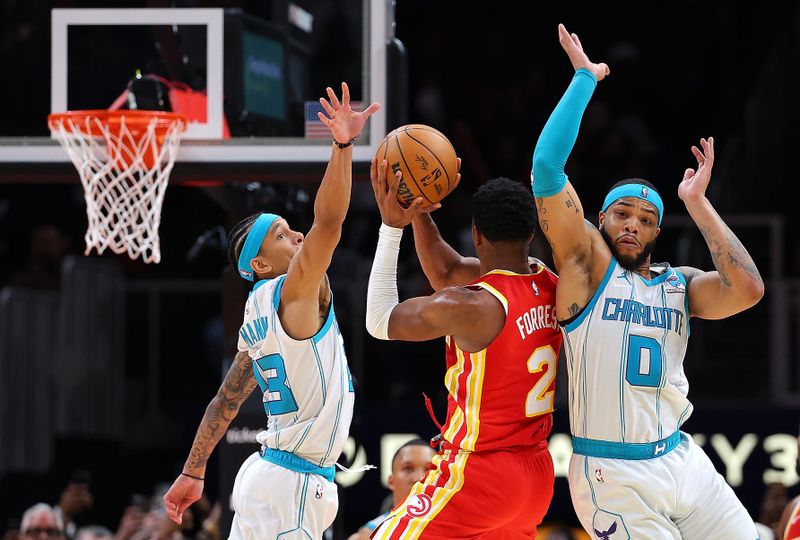 ATLANTA, GEORGIA - APRIL 10:  Trent Forrest #2 of the Atlanta Hawks fails to get off a shot as he is defended by Miles Bridges #0 and Tre Mann #23 of the Charlotte Hornets as time expires in the fourth quarter at State Farm Arena on April 10, 2024 in Atlanta, Georgia.  NOTE TO USER: User expressly acknowledges and agrees that, by downloading and/or using this photograph, user is consenting to the terms and conditions of the Getty Images License Agreement.  (Photo by Kevin C. Cox/Getty Images)