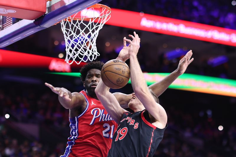 PHILADELPHIA, PENNSYLVANIA - DECEMBER 22: Joel Embiid #21 of the Philadelphia 76ers blocks Jakob Poeltl #19 of the Toronto Raptors during the first quarter at the Wells Fargo Center on December 22, 2023 in Philadelphia, Pennsylvania. NOTE TO USER: User expressly acknowledges and agrees that, by downloading and or using this photograph, User is consenting to the terms and conditions of the Getty Images License Agreement. (Photo by Tim Nwachukwu/Getty Images)