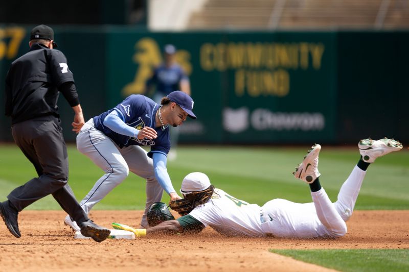 Aug 22, 2024; Oakland, California, USA; Oakland Athletics right fielder Lawrence Butler (4) slides safely into second base with a steal ahead of the tag by Tampa Bay Rays second baseman Christopher Morel (24) during the third inning at Oakland-Alameda County Coliseum. Umpire is Tripp Gibson (73). Mandatory Credit: D. Ross Cameron-USA TODAY Sports