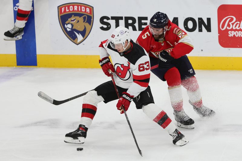 Jan 13, 2024; Sunrise, Florida, USA; New Jersey Devils left wing Jesper Bratt (63) protects the puck from Florida Panthers defenseman Aaron Ekblad (5) during the third period at Amerant Bank Arena. Mandatory Credit: Sam Navarro-USA TODAY Sports